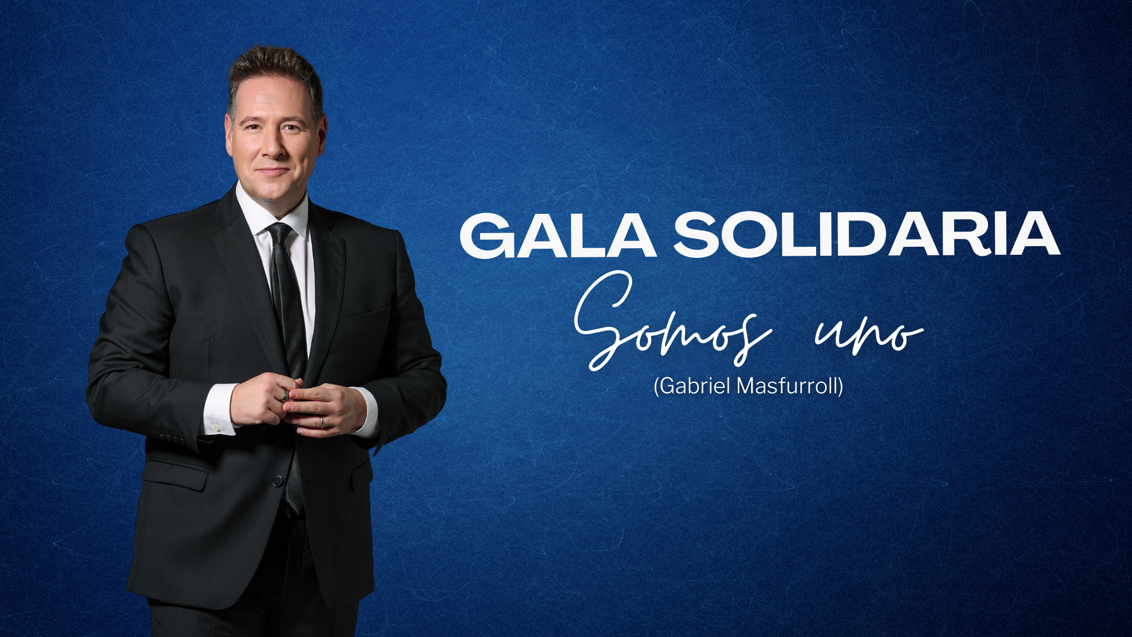 Carlos Latre con traje negro frente al fondo azul como presentador de la Gala Solidaria "Somos Uno" de Gabriel Masfurroll.