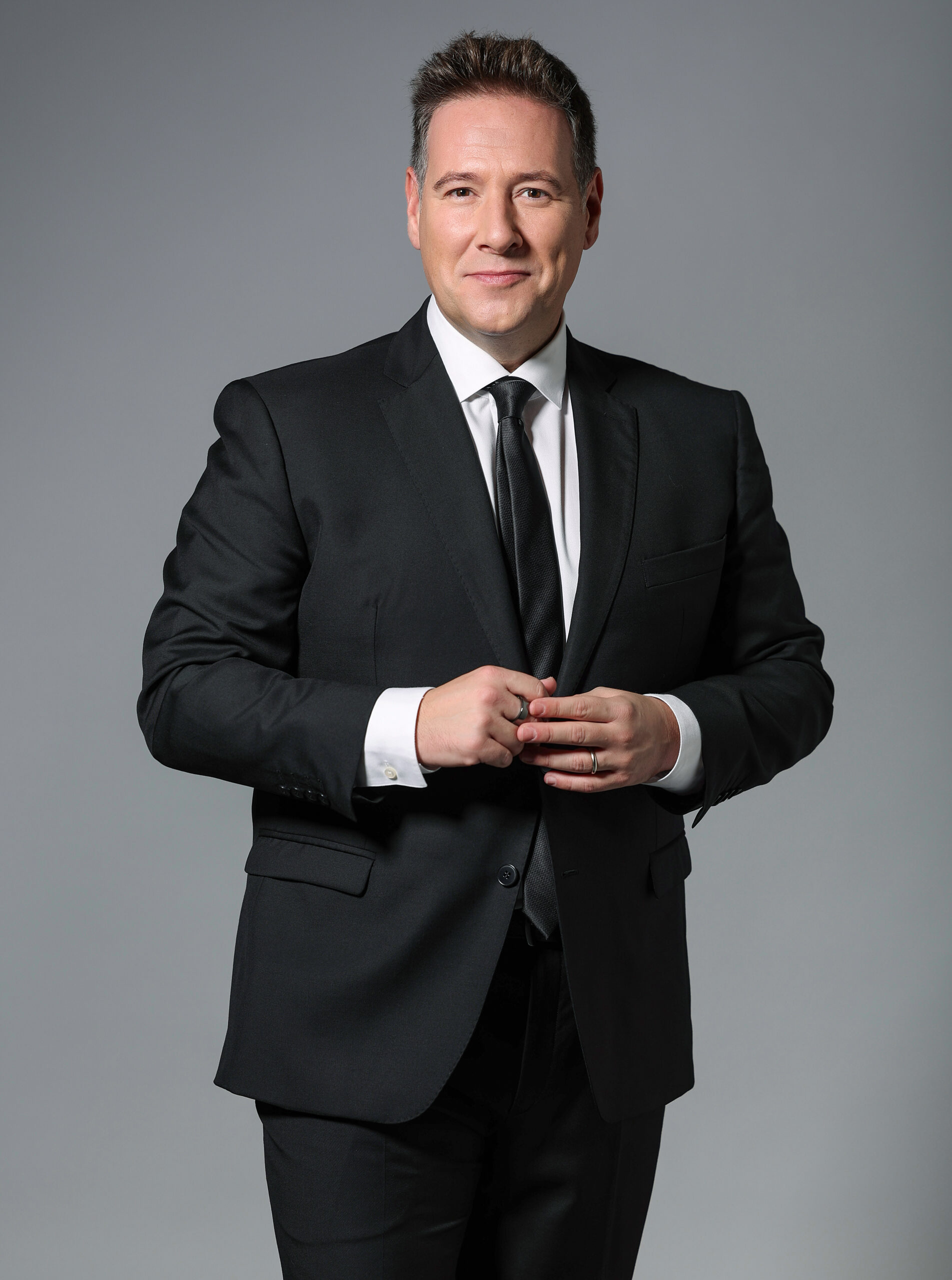 Retrato profesional de Carlos Latre posando con traje oscuro, utilizado para anunciar su participación en el homenaje organizado por la UNED de Vila-real en el Grao de Castelló